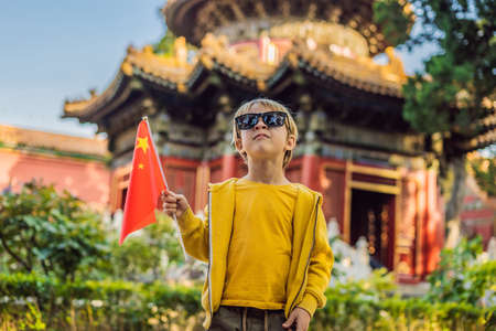 Enjoying vacation in China. Young boy with national chinese flag in Forbidden City. Travel to China with kids concept.の写真素材