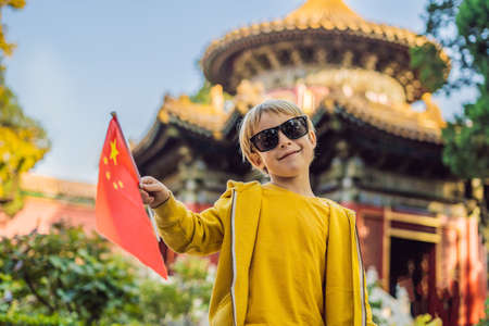 Enjoying vacation in China. Young boy with national chinese flag in Forbidden City. Travel to China with kids concept.の写真素材