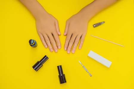 Woman Hands Care. Top View Of Beautiful Smooth Womans Hands With Professional Nail Care Tools For Manicure On yellow Background. Closeup Of Healthy Female Nails With yellow Nail Polish. High Resolutionの写真素材
