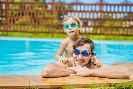 Dad and son in swimming Goggles have fun in the poolの写真素材