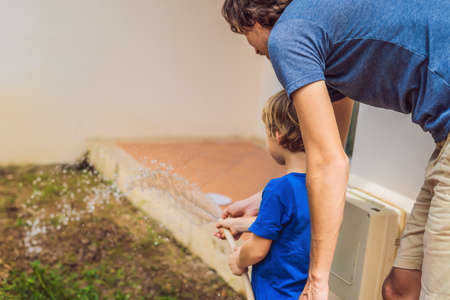 Cute little toddler boy watering plants with watering can in the garden. Adorable little child helping parents to grow vegetables and having fun. Activities with children outdoorsの写真素材