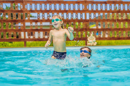 Dad and son in swimming Goggles have fun in the poolの写真素材