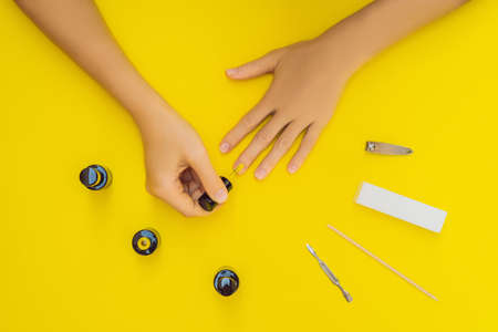 Woman Hands Care. Top View Of Beautiful Smooth Womans Hands With Professional Nail Care Tools For Manicure On yellow Background. Closeup Of Healthy Female Nails With yellow Nail Polish. High Resolutionの写真素材