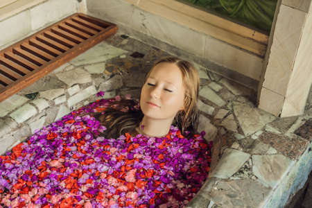 Attractive Young woman in bath with petals of tropical flowers and aroma oils. Spa treatments for skin rejuvenation. Alluring woman in Spa salon. Luxury spa and skin careの写真素材