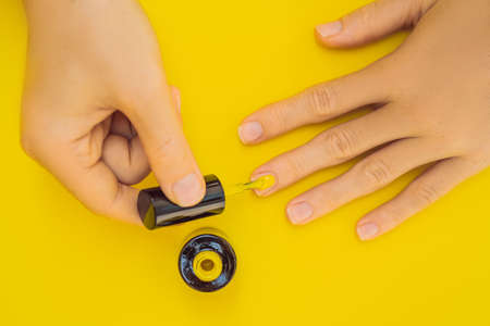 Woman Hands Care. Top View Of Beautiful Smooth Womans Hands With Professional Nail Care Tools For Manicure On yellow Background. Closeup Of Healthy Female Nails With yellow Nail Polish. High Resolutionの写真素材