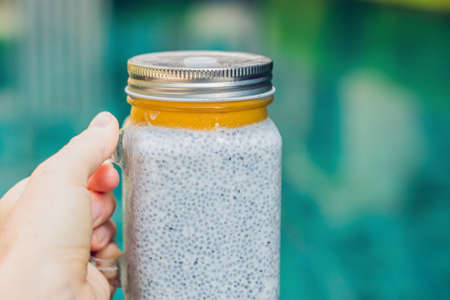 Healthy layered dessert with chia pudding and mango morning on the background of the poolの写真素材