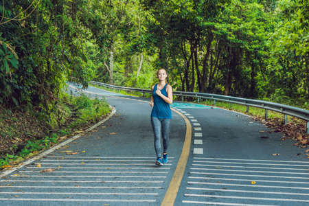 Sporty woman running on road at sunrise. Fitness and workout wellness concept