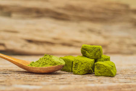 Matcha powder and candy made of matcha on wooden background. Homemade Matcha