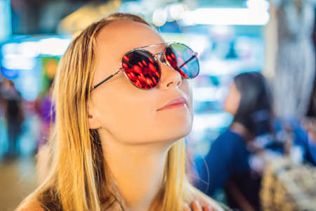 Woman celebrate Chinese New Year look at Chinese red lanterns. Chinese lanterns are reflected in glassesの写真素材