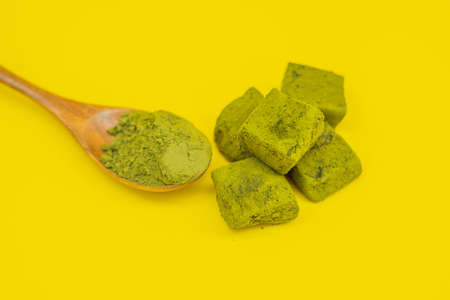 Matcha powder and candy made of matcha on yellow background. Homemade Matcha