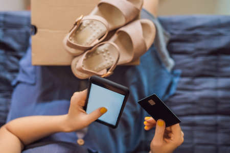 young woman received online shopping parcel opening boxes and buying fashion items by using credit cardの写真素材