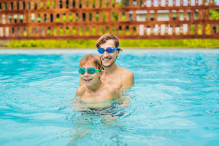 Dad and son in swimming Goggles have fun in the poolの写真素材