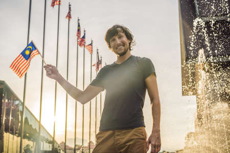 Young man travels in Malaysia. Holds the Malaysian flag