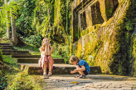 Mom and son on background of Gunung Kawi. Ancient carved in the stone temple with royal tombs. Bali, Indonesia. Traveling with children conceptの写真素材
