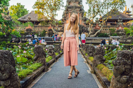 Young woman traveler in the background of Pura Taman Kemuda Saraswati Temple in Ubud, Bali island, Indonesiaの写真素材