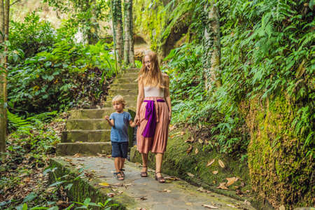 Mom and son on background of Gunung Kawi. Ancient carved in the stone temple with royal tombs. Bali, Indonesia. Traveling with children conceptの写真素材