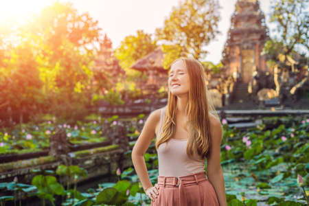 Young woman traveler in the background of Pura Taman Kemuda Saraswati Temple in Ubud, Bali island, Indonesia with sunlightの写真素材