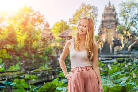 Young woman traveler in the background of Pura Taman Kemuda Saraswati Temple in Ubud, Bali island, Indonesia with sunlightの写真素材