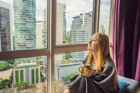 Woman wrapped in a blanket and looking at the big cityの写真素材