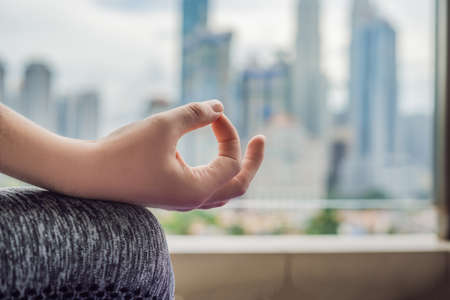 Young woman is practicing yoga in the morning on her balcony with a panoramic view of the city and skyscrapersの写真素材