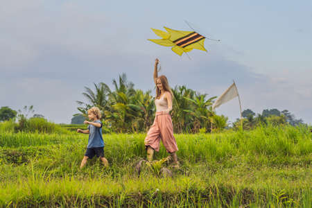 Mom and son launch a kite in a rice field in Ubud, Bali Island, Indonesiaの写真素材