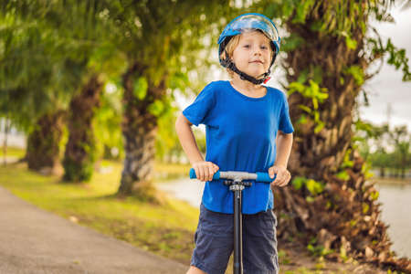 Boy riding scooters, outdoor in the park, summertime. Kids are happy playing outdoorsの写真素材