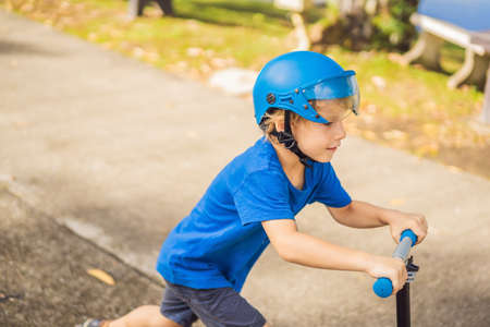 Boy riding scooters, outdoor in the park, summertime. Kids are happy playing outdoors