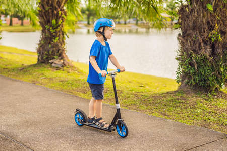 Boy riding scooters, outdoor in the park, summertime. Kids are happy playing outdoors