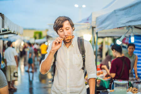 Young man tourist on Walking street Asian food marketの写真素材