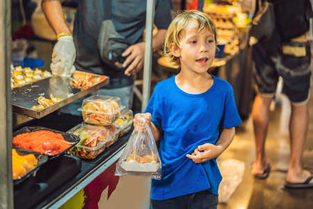 Young boy tourist on Walking street Asian food marketの写真素材