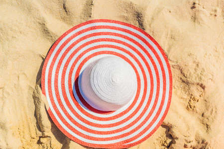 Top view of sandy beach with red striped beach hat Background with copy space and visible sand textureの写真素材