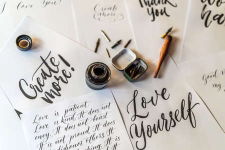 Paper, ink, calligraphy pens and inscriptions. Lettering workshop details. Inscribing ornamental decorated letters. Calligraphy, graphic design, lettering, handwriting, creation conceptの写真素材