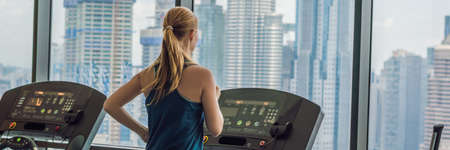 sport, fitness, lifestyle, technology and people concept - woman exercising on treadmill in gym against the background of a big city. BANNER, LONG FORMATの写真素材