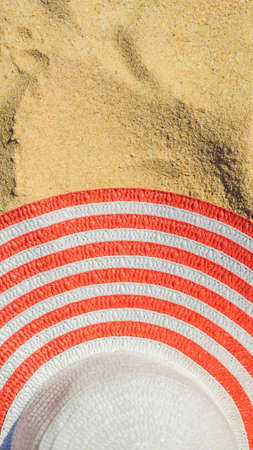 Top view of sandy beach with red striped beach hat Background with copy space and visible sand...