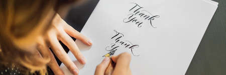 Calligrapher hands writes phrase on white paper. Phrase - Thank you. Inscribing ornamental decorated...