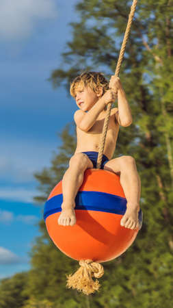 A boy on a swing on the beach. Mom and son spend time on the beach VERTICAL FORMAT for mobile story or stories size. Mobile wallpaperの写真素材