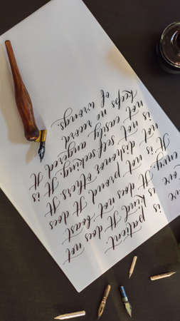 Calligrapher hands writes phrase on white paper. Bible phrase about love Inscribing ornamental...