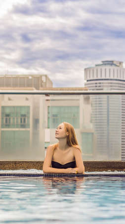 Young woman in the pool among the skyscrapers and the big city. Relax in the big city. Rest from stress VERTICAL FORMAT for mobile story or stories size. Mobile wallpaperの写真素材