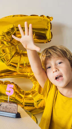 Happy little kid boy celebrating his birthday and blowing candles on homemade baked cake, indoor. Birthday party for children. Carefree childhood, anniversary, happiness. Five years old VERTICAL FORMAT for mobile story or stories size. Mobile wallpaperの写真素材