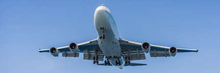 A white airplane flying in a clear pale blue sky BANNER, LONG FORMATの写真素材