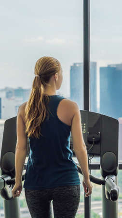 sport, fitness, lifestyle, technology and people concept - woman exercising on treadmill in gym...