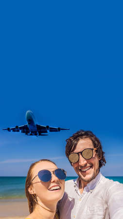 Man and woman tourists have fun on the beach watching the landing planes. Traveling on an airplane concept. Text space. Island Phuket in Thailand. Impressive paradise. Hot beach Mai Khao. Amazing landscape VERTICAL FORMAT for mobile story or stories size. Mobile wallpaperの写真素材