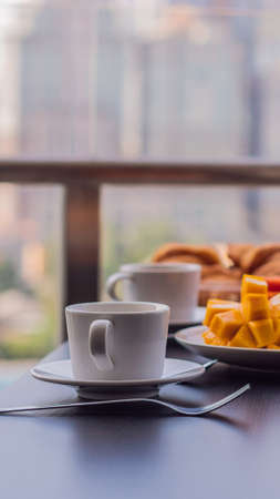 Breakfast table with coffee fruit and bread croisant on a balcony against the backdrop of the big city VERTICAL FORMAT for mobile story or stories size. Mobile wallpaperの写真素材