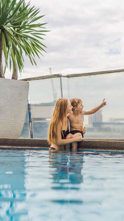 Mother and son in the pool among the skyscrapers and the big city. Relax in the big city. Rest from stress VERTICAL FORMAT for mobile story or stories size. Mobile wallpaperの写真素材