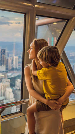 Mom and son are looking at Kuala lumpur cityscape. Panoramic view of Kuala Lumpur city skyline evening at sunset skyscrapers building in Malaysia. Traveling with kids concept VERTICAL FORMAT for mobile story or stories size. Mobile wallpaperの写真素材