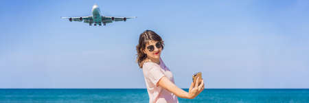 Woman makes a selfie on the beach watching the landing planes. Traveling on an airplane concept....