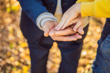 A childs hand holding the hand of an old man