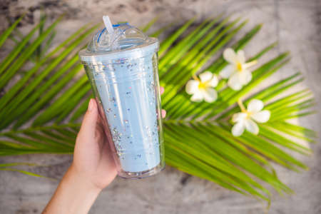 Glass for drink with glitter on tropic background