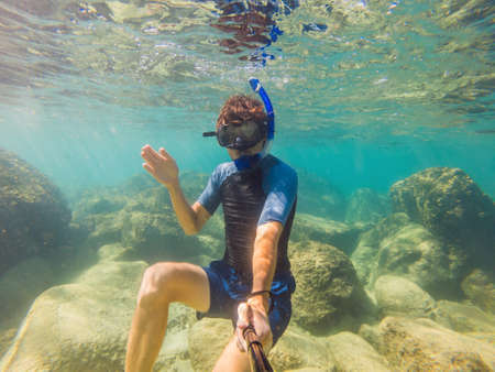 Young men snorkeling exploring underwater coral reef landscape  in the deep blue ocean with colorful...