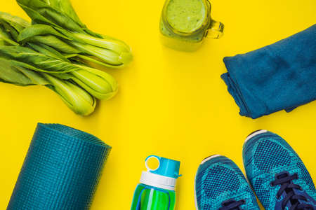 Everything for sports turquoise, blue shades on a yellow background and spinach smoothies. Yoga mat, sport shoes sportswear and bottle of water. Concept healthy lifestyle, sport and diet. Sport equipment. Copy space.の写真素材